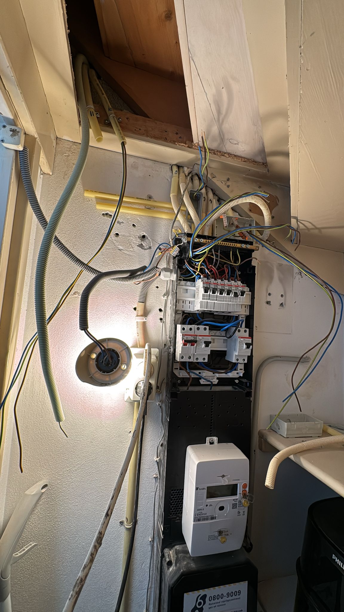 Meterkast tijdens het werk, met losse kabels uit het plafond